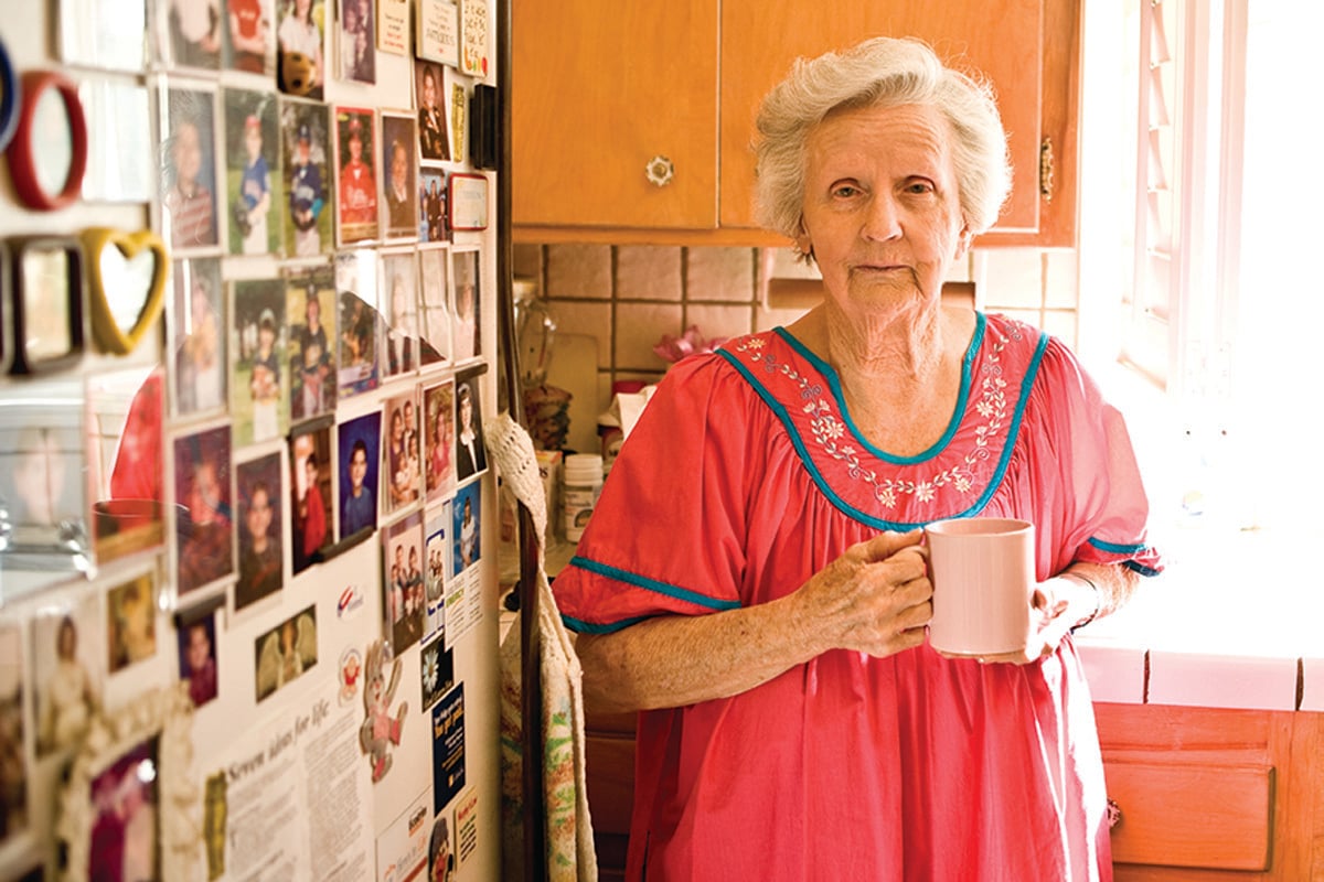 Elderly woman in her kitchen holding a cup of coffee