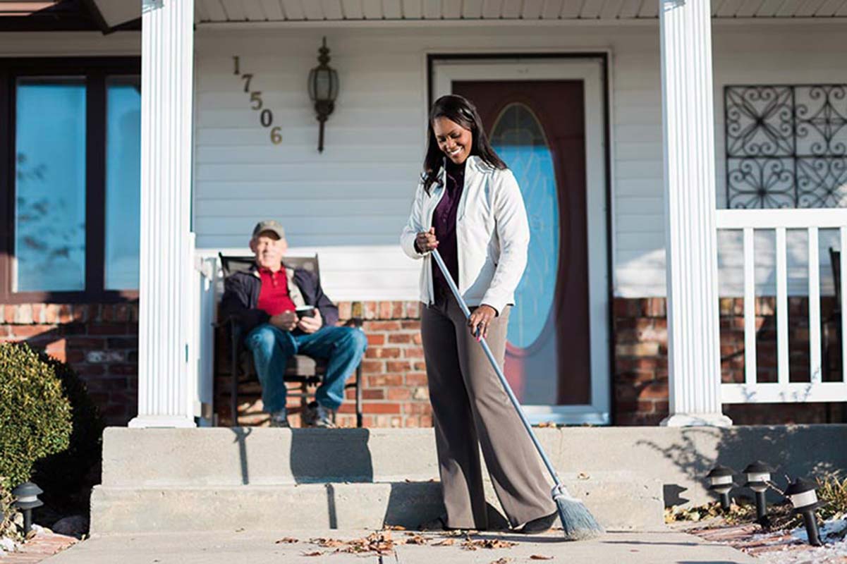 Caregiver cleans home entrance while accompanying senior