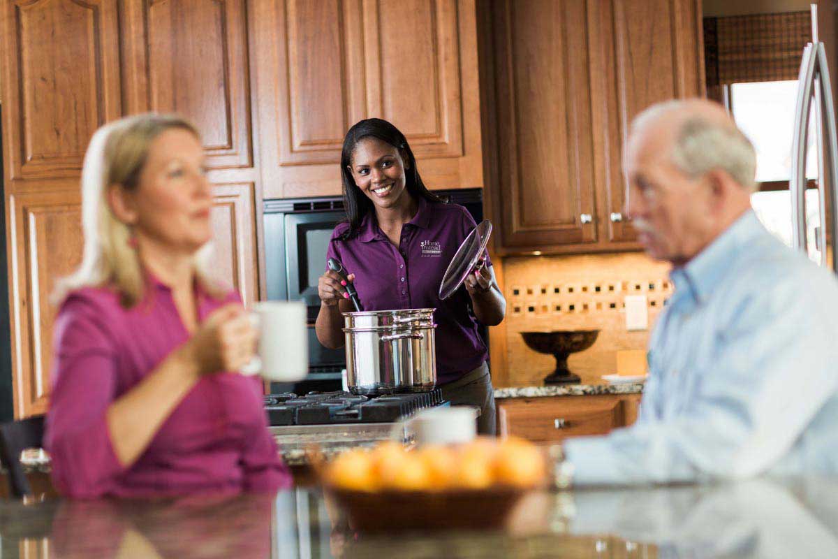 Daughter spending quality time with dad while caregiver cooks