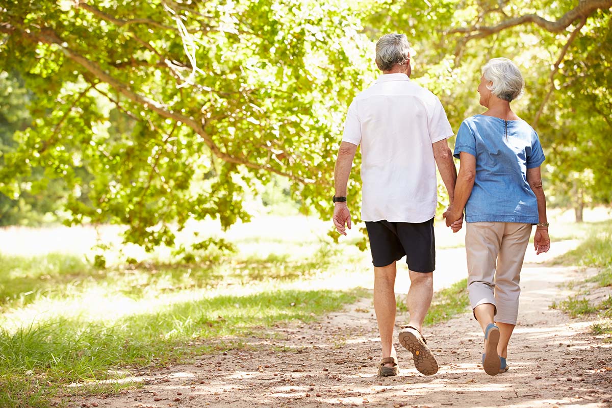 Seniors holding hands, walkig in the outdoors