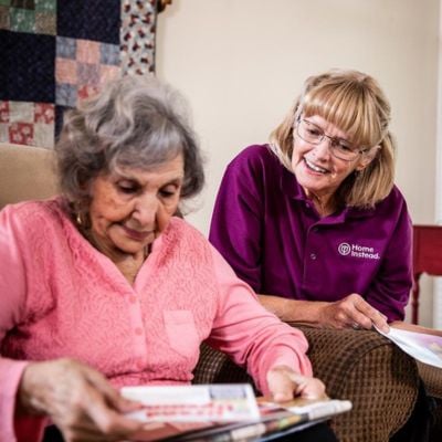 home instead caregiver assisting senior client sort through mail