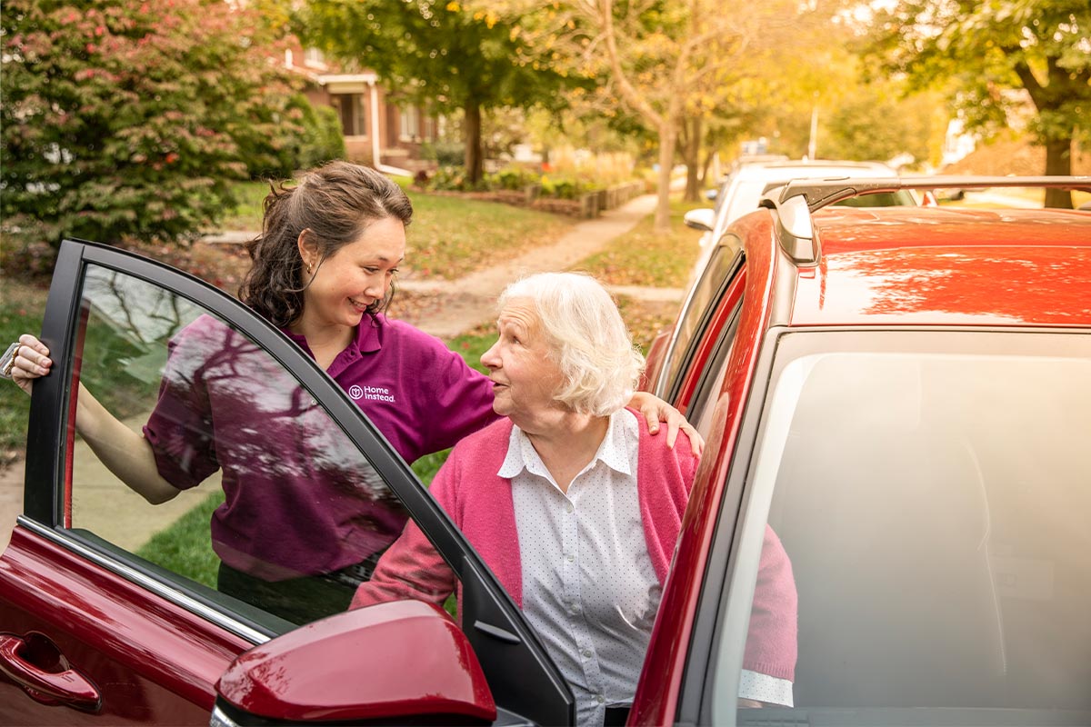 home instead caregiver helps senior woman get out of car